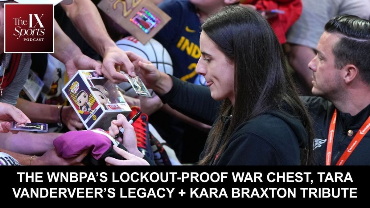 Caitlin Clark focuses on signing a shirt while surrounded by fans holding other items to sign.